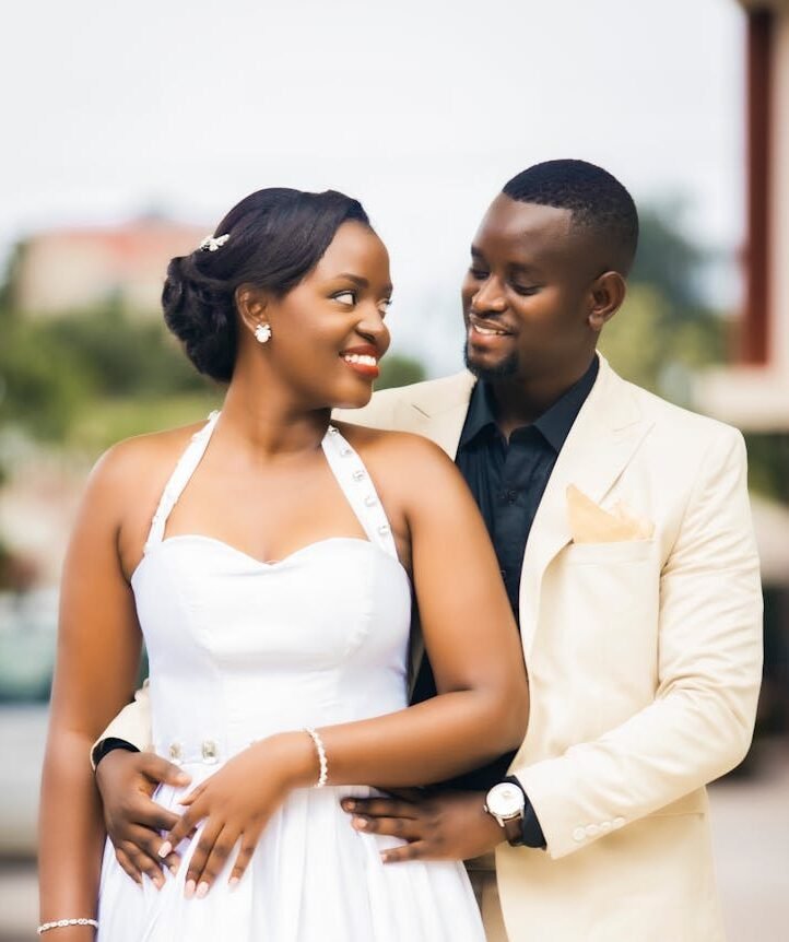 Home Bride and groom posing lovingly outdoors in elegant attire.